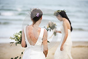 Two brides with bouquets at the beach