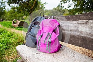 Two bright backpacks stand on a wooden bench in the street. Outdoor recreation. Trekking in the mountains, couple on vacation