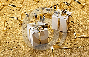 Two bright christmas gifts on gold background with serpentine, tinsel and confetti