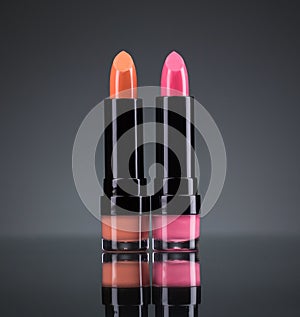 Two bright lipsticks on a black