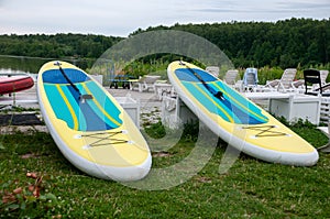 Two bright surfboards lie on the green grass after or before training