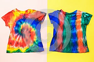 Two bright tie dye t-shirts on a red and yellow background. Flat lay.