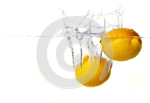 Two bright yellow lemons dropped in water