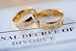 Two broken golden wedding rings divorce decree document