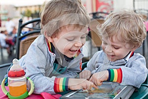 Two brother toddler boys playing with tablet pc