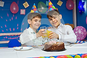 Two brothers banging glasses of juice at a birthday party