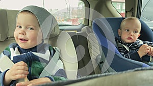 Two brothers boys brothers sitting in back car seats. As brothers sitting in back car seats travelling engage in