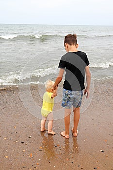 Two brothers children playing on the sand beach by the sea