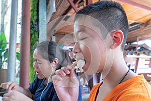 Two brothers are eating grilled shrimp