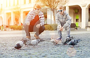 Two brothers feed a doves on the old city square