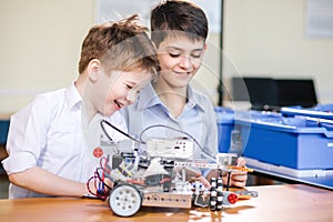 Two brothers kids playing with robot toy at school robotics class, indoor.