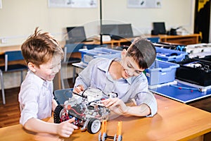 Two brothers kids playing with robot toy at school robotics class, indoor.