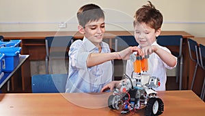 Two brothers kids playing with robot toy at school robotics class, indoor.