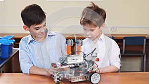 Two brothers kids playing with robot toy at school robotics class, indoor.