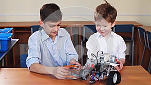 Two brothers kids playing with robot toy at school robotics class, indoor.