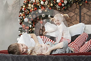 Two brothers and little sister on large bed on Christmas Eve. Children siblings are waiting for Santa Claus