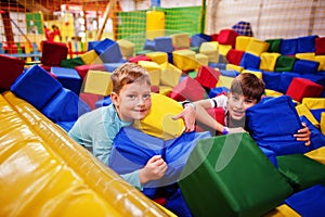 Two brothers lying on pool with colored foam cubes in indoor play center