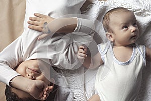 Two brothers lying and posing. Portrait of brothers. Two months baby boy and five years small boy playing cheerfully. View from