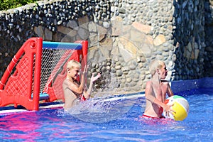 Two brothers playing with ball in swimming pool