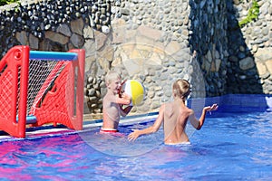 Two brothers playing with ball in swimming pool