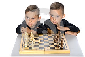 Two little boys play chess.