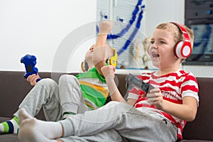 Two brothers playing in the headphones joysticks in video games.
