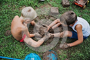 Two brothers playing with mud