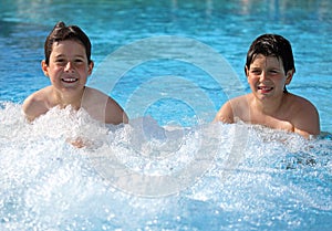 Two brothers playing in the pool in summer