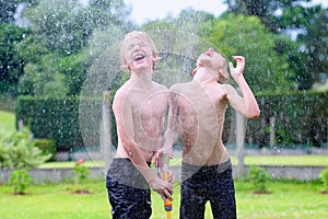 Two brothers playing with water hose in the garden