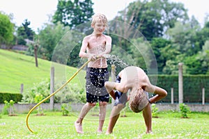 Two brothers playing with water hose in the garden