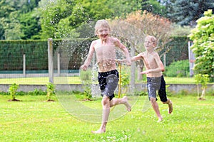 Two brothers playing with water hose in the garden