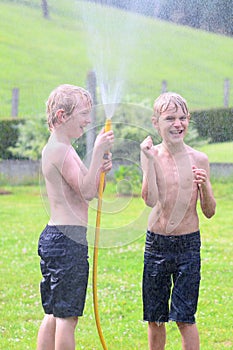 Two brothers playing with water hose in the garden
