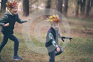 Two Brothers running in a forest on autumn day. Boys have a crow