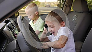 Two brothers are sitting behind the wheel of a car in the front with a phone.