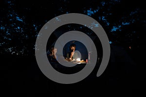 Two brothers sitting by a tent with a dimmed light