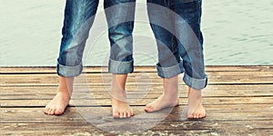 Two brothers stand barefoot on the wooden pier .Family vacation on the lake.