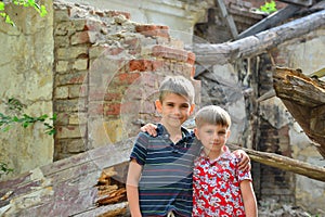 Two brothers stand in an embrace, orphans are left without housing and stand near the ruins of the building as a result of a milit