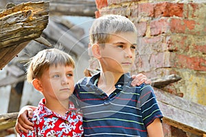 Two brothers stand near the ruined house, the concept of natural disaster, fire, and devastation.