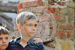 Two brothers stand near the ruined house, the concept of natural disaster, fire, and devastation.