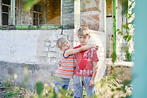 Two brothers are standing near a burned-out house, who lost their homes as a result of hostilities and natural disasters