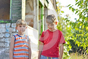 Two brothers are standing near a burned-out house, who lost their homes as a result of hostilities and natural disasters