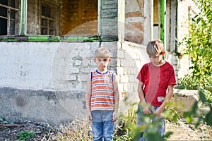 Two brothers are standing near a burned-out house, who lost their homes as a result of hostilities and natural disasters