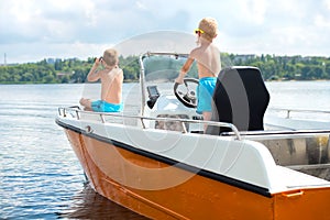 Two brothers swim on a motor boat on the lake.