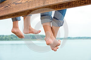 Two brothers swung their legs from the wooden pier .Family vacation on the lake.