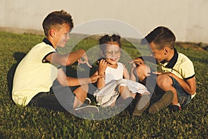Two brothers tickle their sister in nature. horizontal frame