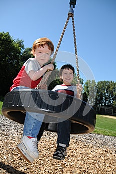 Two brothers on a tire swing