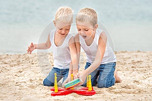 Two brothers are walking and playing on the beach.The game is a ring toss.