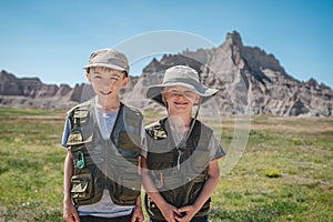 Two brothers wearing junior ranger vests in front of rock formations in Badlands National Park