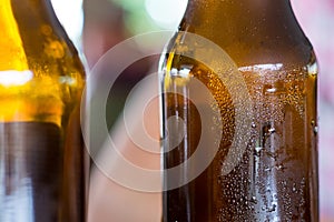 Two brown beer bottle dark perspiring close-up, background basis pub