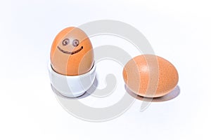 Two brown chicken eggs with positive face smiling in an egg stand and lie on white background. Drawn black smile